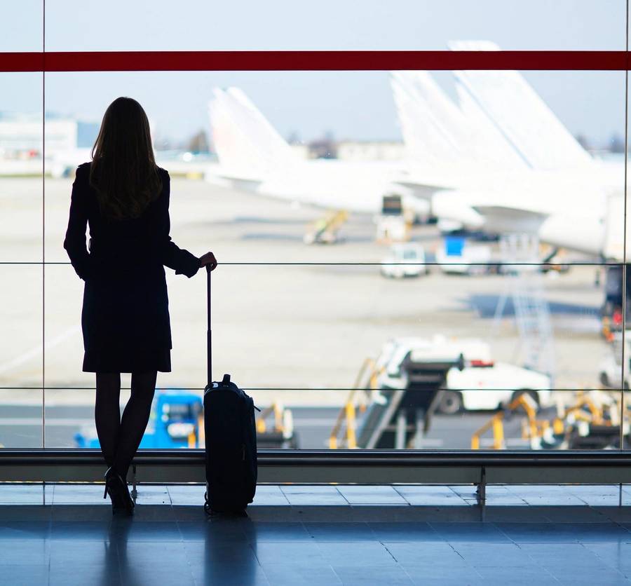 Young woman in the airport, looking through the window at planes